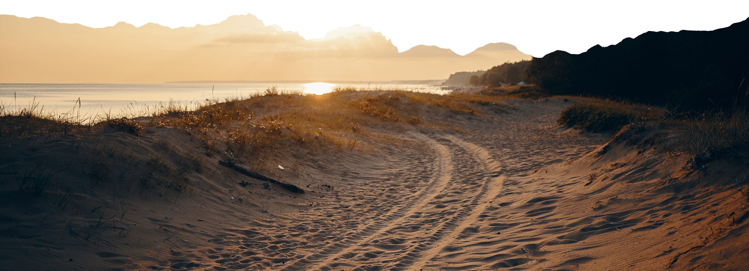 Car traveling through the desert, dusty road under the sun.